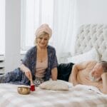 Para relaksuje się w jasnej sypialni z tybetańską misą dźwiękową