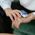 Pulsoksymetr na palcu dorosłej osoby mierzący poziom tlenu we krwi