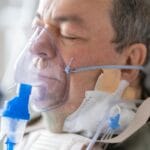 Starsza pacjentka w szpitalu z maską tlenową na twarzy