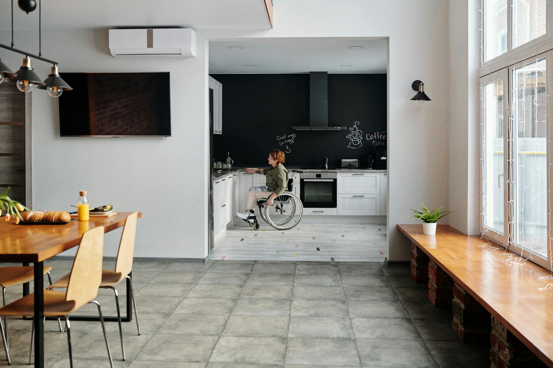 Kobieta na wózku inwalidzkim gotuje w nowoczesnej, jasnej kuchni