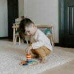 Małe dziecko bawiące się kolorową zabawką edukacyjną w przytulnym pokoju