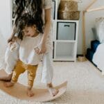 Mama bawi się z synem na drewnianej desce równoważnej w pokoju Montessori