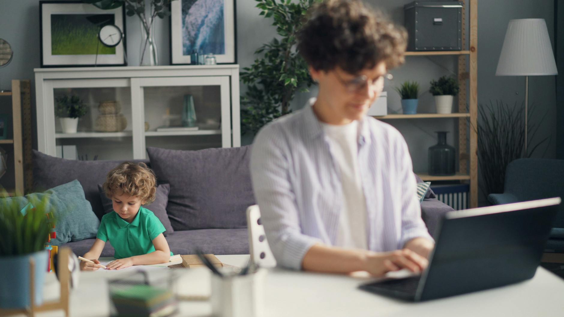 Mama pracuje przy laptopie, a syn bawi się w tle