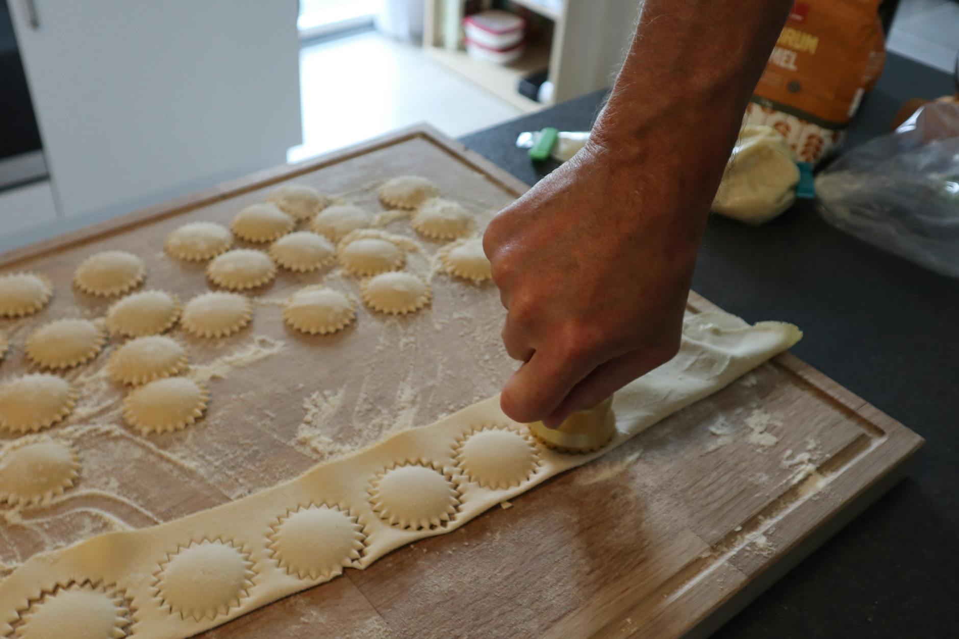 Osoba lepi domowe ravioli na oprószonej mąką stolnicy