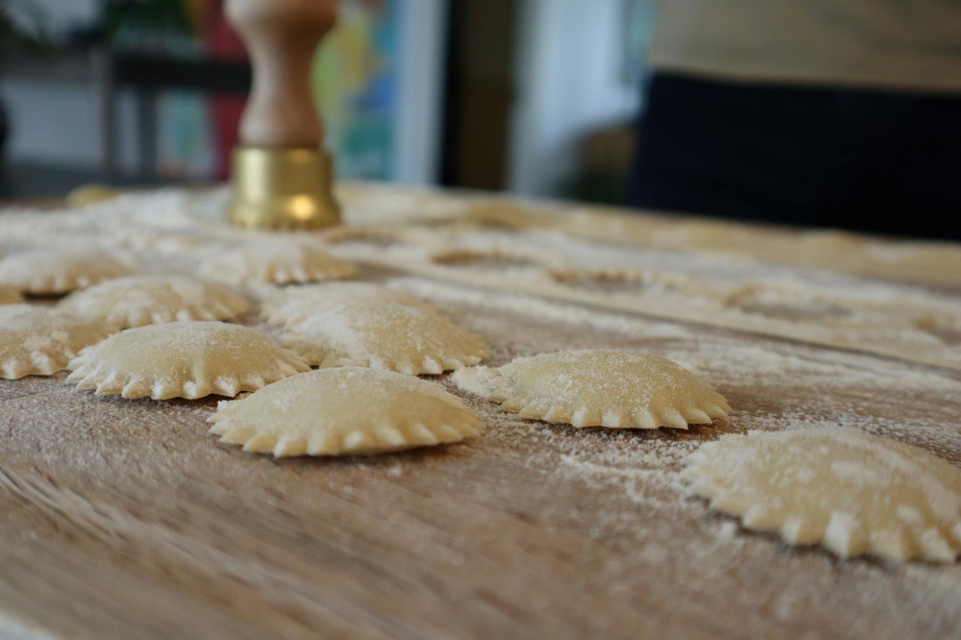 Surowe ravioli na oprószonej mąką desce, przygotowane do gotowania