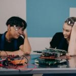 Dwóch młodych techników przy stanowisku pracy projektuje układ elektroniczny