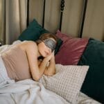 Kobieta śpiąca spokojnie w łóżku z opaską na oczy w przytulnej sypialni