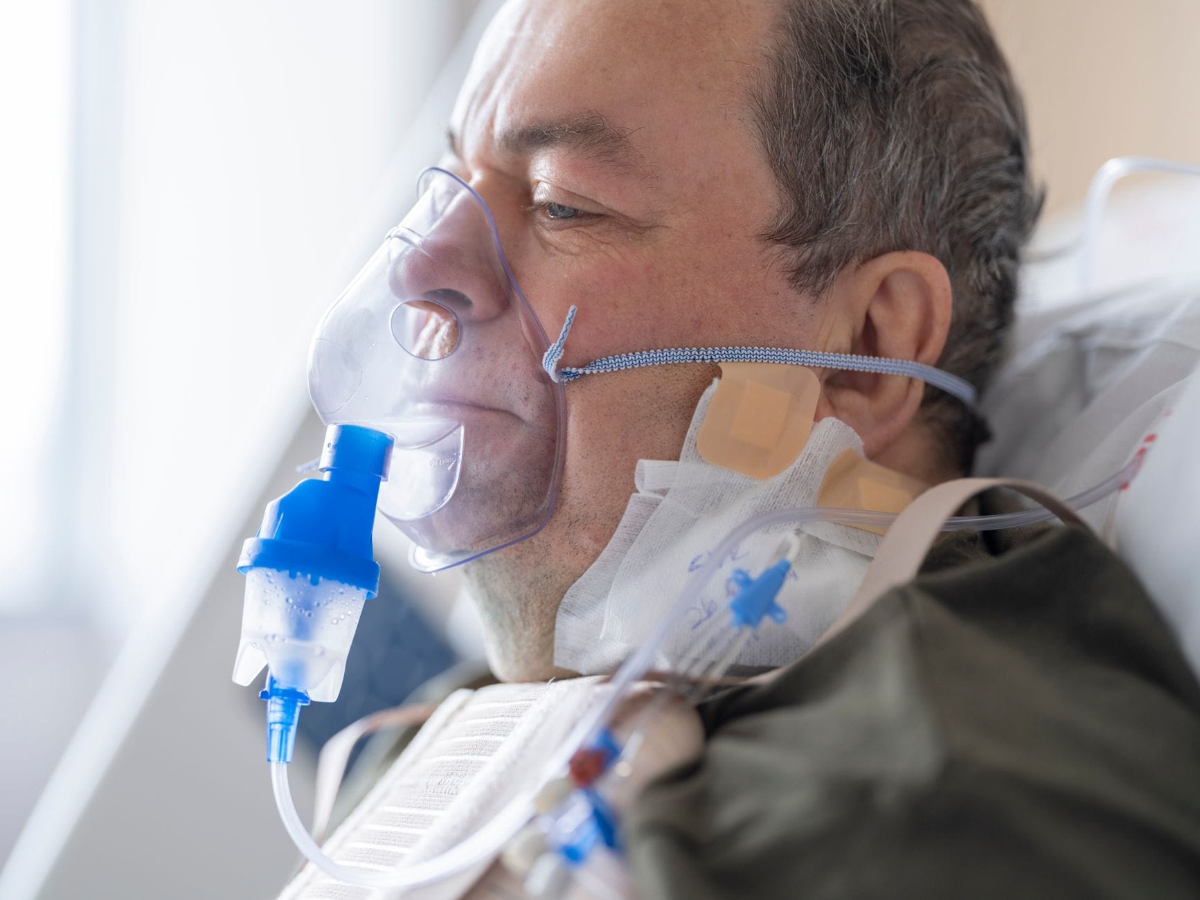 Starsza pacjentka w szpitalnym łóżku z maską tlenową