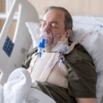 Starszy mężczyzna w łóżku szpitalnym z maską tlenową