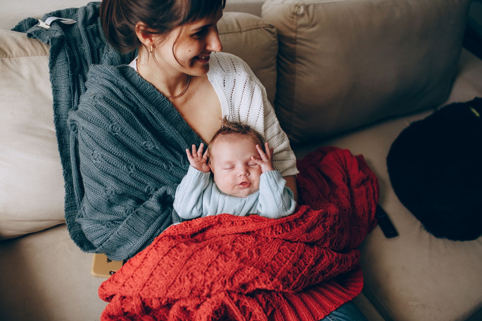 Mama trzyma śpiącego noworodka otulonego miękkim kocykiem Mama trzyma śpiącego noworodka otulonego miękkim kocykiem