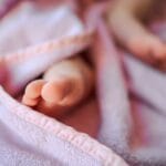 Stópki noworodka otulone miękkim różowym kocykiem