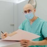 Lekarz w maseczce wypełnia dokumentację medyczną związaną z tlenoterapią