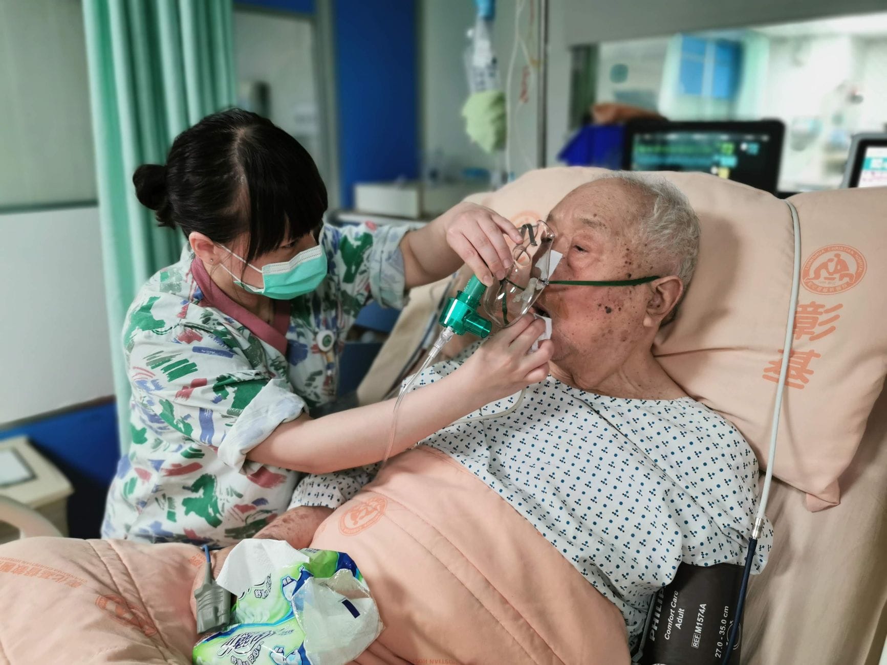 Psychologiczne aspekty życia z tlenoterapią domową: jak nie dać się przygnębieniu Pielęgniarka wspiera seniora z maską tlenową na łóżku szpitalnym